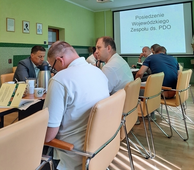 Zdjęcie przedstawia osoby siedzące za stołem.