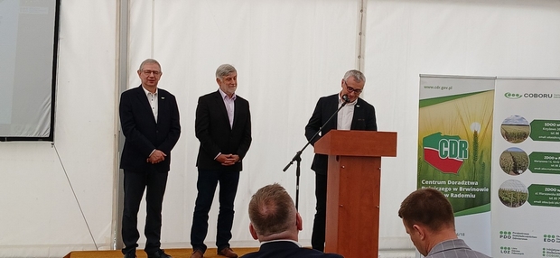 Po lewej stronie stoi prof. dr hab. Henryk Bujak dyrektor COBORU, obok niego stoi Krzysztof Smaczyński – Z-ca dyr. Departamentu Hodowli i Ochrony Roślin MRiRW. Po prawej stronie, za mównicą stoi Arkadiusz Kalinowski, dyrektor SDOO w Krzyżewie.